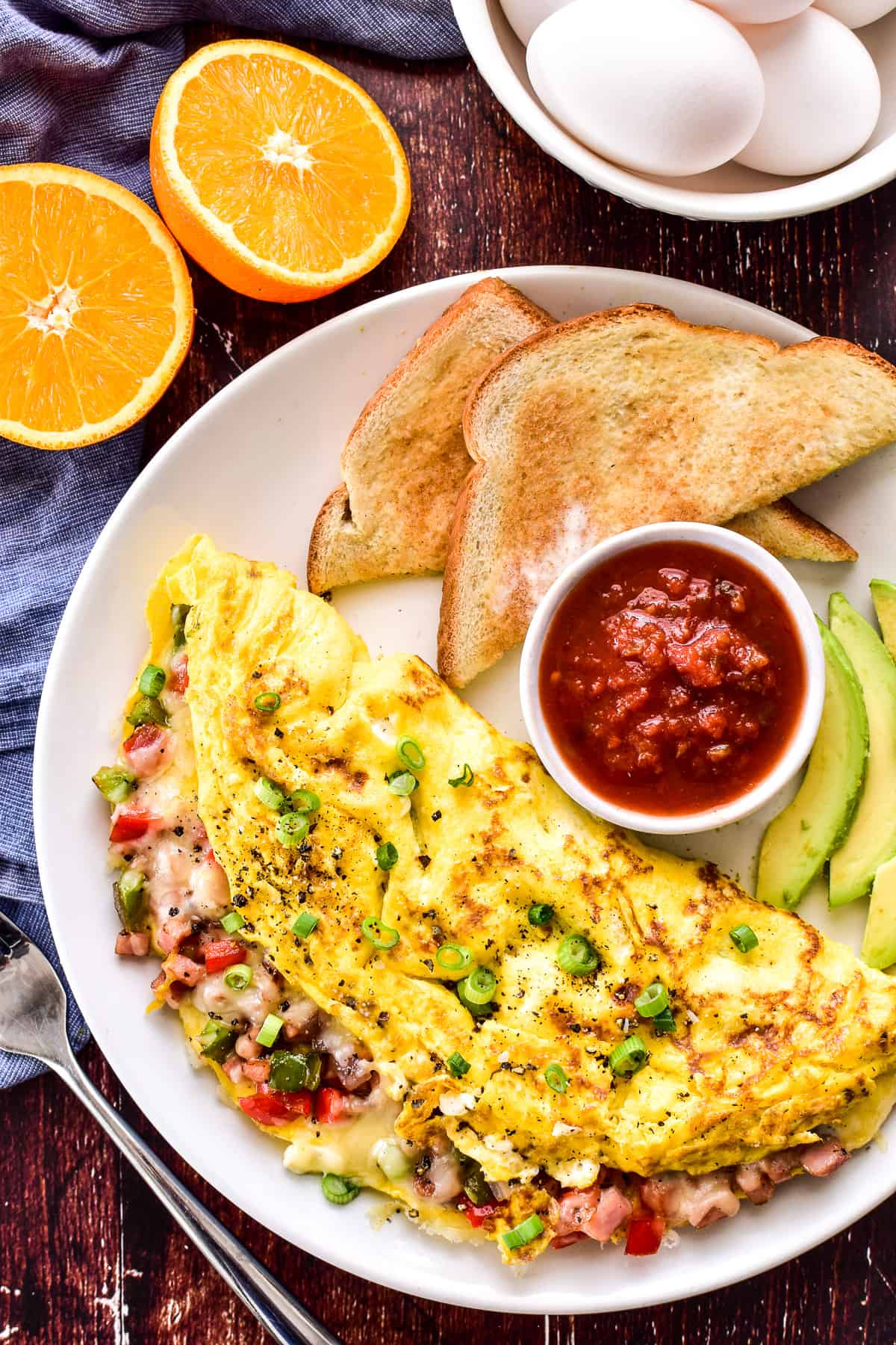 Western Omelette on a plate with salsa, avocado slices, and toast
