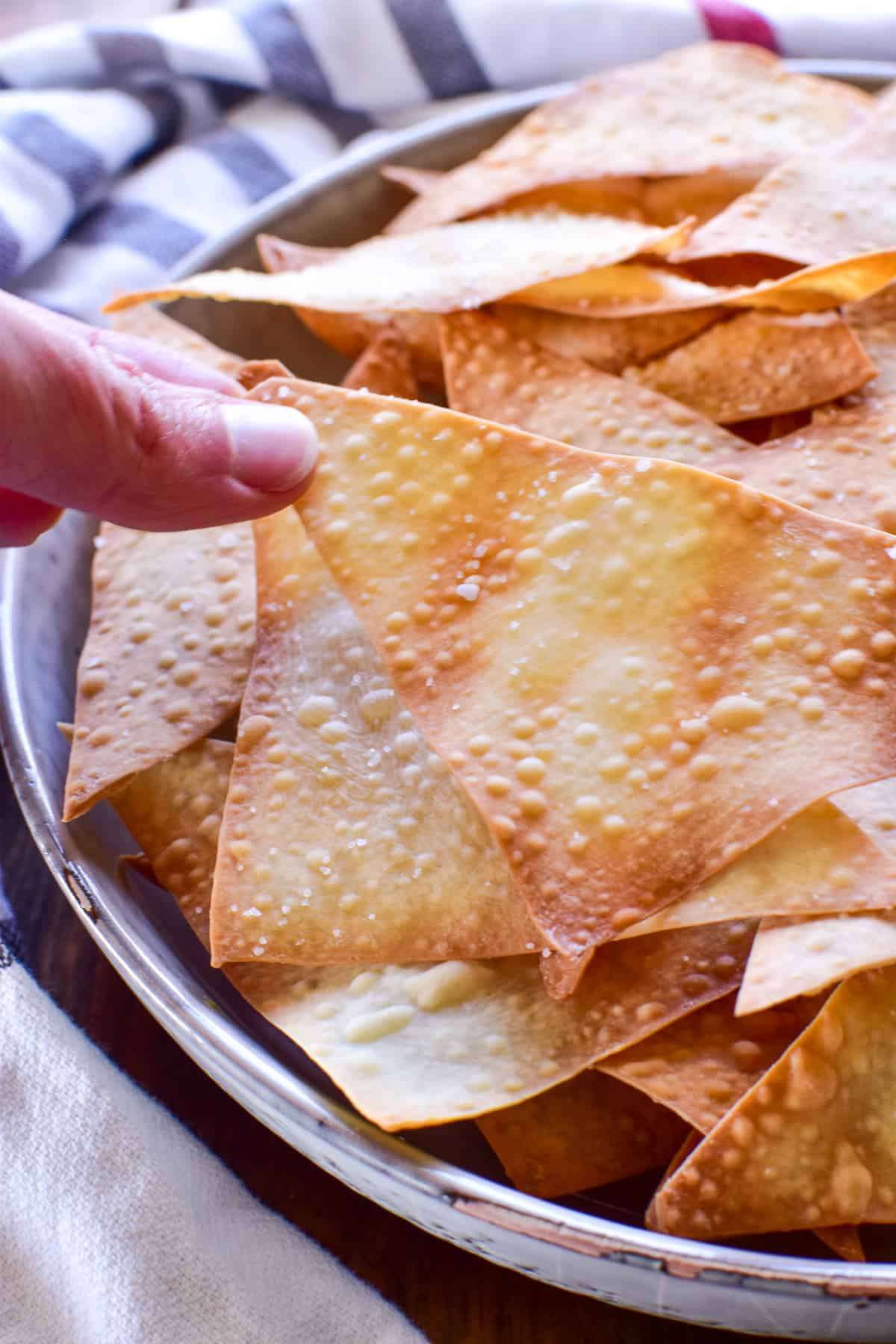 Photo of hand grabbing a Baked Wonton Chip from a bowl